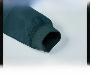 Détail du tissu en maille respirant et des poignets élastiques côtelés sur la veste verte
