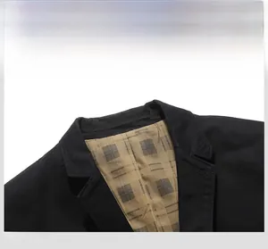 Detail view of the notch lapel on a black men's blazer with khaki plaid lining texture
