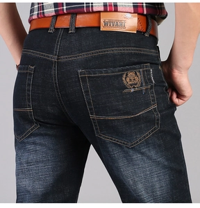 Dettaglio dei jeans blu scuro con patch in pelle in vita e ricamo vintage sulla tasca