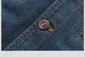 Detailed macro view of bronze fashion button and yellow stitching on dark blue denim jacket
