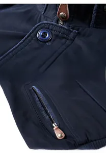 Detailaufnahme von Stehkragen, klassischem Metallreißverschluss und Tasche mit Lederlasche