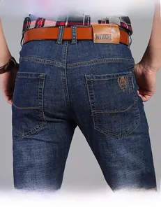 Dettaglio di jeans dritti blu scuro con ricamo sulla tasca posteriore e cintura in vera pelle