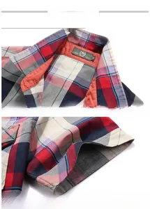 Detail view of cotton plaid shirt lapel collar with red fabric piping and precise stitching