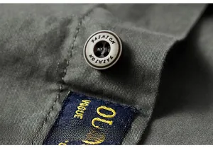 Macro shot of olive green cotton shirt featuring resin button and embroidered woven label
