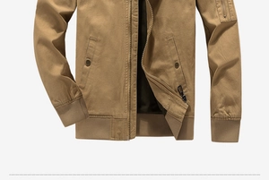 Detail of khaki cotton jacket showing metal zipper and ribbed cuffs on white background