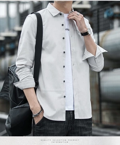 Detail of light gray long sleeve shirt with contrast black buttons and textured fabric