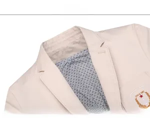 Detail der khakifarbene Baumwolljacke mit gesticktem Wappen und gemustertem Innenfutter