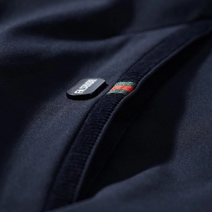Men's baseball collar jacket detail featuring deep blue fabric with striped pocket accent