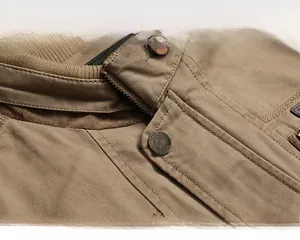 Detailed macro view of men's khaki outdoor jacket collar with textured canvas and metal zipper