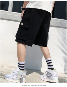 Detail shot of black cargo shorts featuring large side pockets with flap and woven label