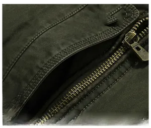 Detailed close-up of dark olive cotton jacket showing brass metal zipper and side pocket