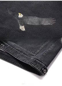 Détails de l'imprimé aigle et du bouton métallique sur une veste en jean grise
