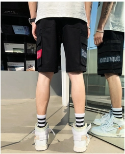 Detail of black cargo shorts featuring Supremo embroidery and large utility side pockets