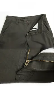 Détail du pantalon cargo vert militaire avec bouton à la taille et fermeture éclair métal