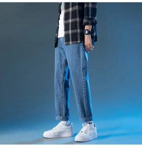 Détail d'un jean bleu droit avec ourlet retroussé et texture denim délavée