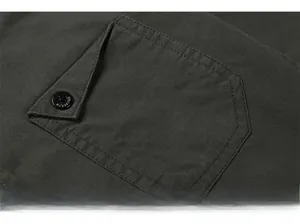 Detail shot of the dark green cotton shirt pocket featuring a black branded button