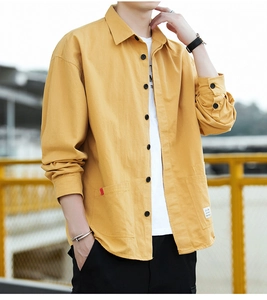 Detail view of ginger yellow cotton shirt with double front pockets and black buttons