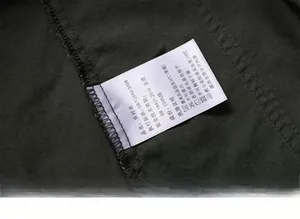 Detail of 100% cotton wash label and premium stitching on dark army green men's shirt