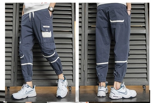 Dettaglio dei pantaloni cargo con tasche laterali, cinghie bianche e polsini elastici
