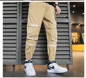 Dettaglio dei pantaloni cargo kaki con tasche utility e coulisse bianca in vita