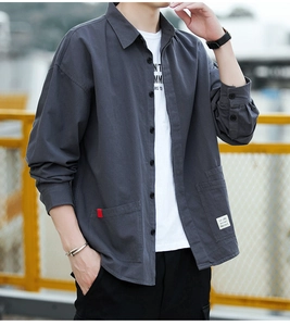 Detail of dark grey cotton cargo shirt featuring dual front pockets and woven letter label