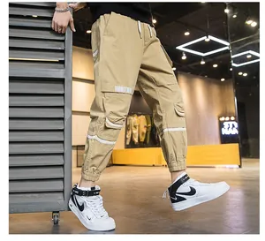 Dettaglio dei pantaloni jogger kaki con grandi tasche laterali e decorazioni a righe