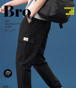 Detail view of large vertical flap pocket and branded woven label on black cargo pants
