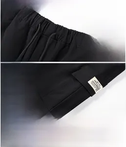 Detail view of black cargo pants showing drawstring waist, flap pocket and fabric texture