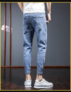 Detail view of light blue slim fit jeans featuring rear pockets and small woven brand label
