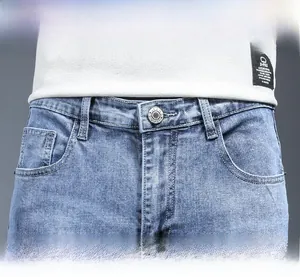 Detailed macro view of light blue slim-fit jeans featuring metal buttons and front pockets