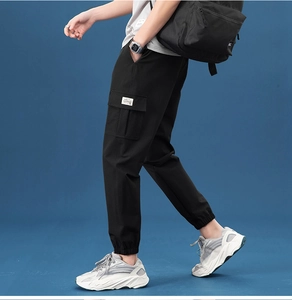 Detail of black cargo pants with side flap pocket and white woven label on side