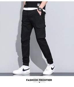Detail of black cotton cargo pants showing large flap pocket and metal zipper decor