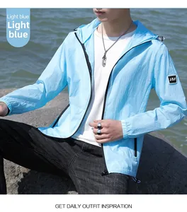 Détail de la veste anti-UV bleu clair avec capuche et patch JSF sur plage rocheuse
