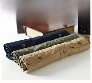 Macro detail of three cotton work shirts with flap pockets in navy, green, and khaki