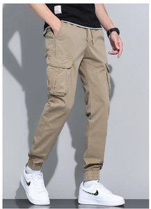 Detail of khaki cargo jogger pants with side flap pockets and elastic cuffs for men
