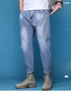 Détail du jean bleu clair délavé avec imprimé graphique blanc et moustaches