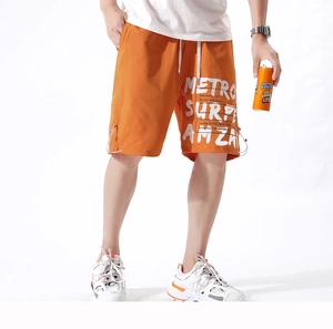 Détail du short d'été orange avec typographie graphique blanche et taille à cordon blanc