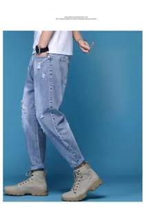 Détail d'un jean jogging bleu clair délavé avec moustaches et écusson en cuir de marque