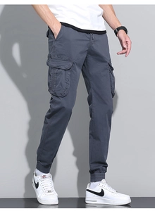 Detail of dark blue men cargo pants with large side flap pockets and elastic cuffs