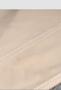 Detailed macro view of khaki woven twill fabric with white double stitching and texture