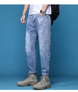 Gros plan d'un jean bleu clair avec imprimé lettres blanches et détails de texture usés
