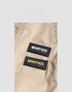 Detail of khaki twill joggers featuring dual rectangular logo patches and fabric texture