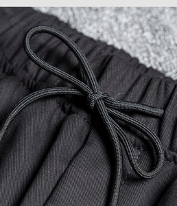 Detail of black jogger pants featuring an elastic waistband and adjustable drawstrings