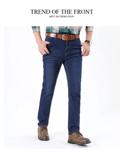 Detail of dark blue men's straight jeans with vintage wash effect and brown leather belt