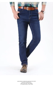 Detail of dark blue straight-leg jeans with contrasting yellow stitching and leather belt