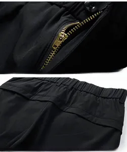 Vue détaillée de la fermeture éclair dorée et des coutures de taille sur le short noir