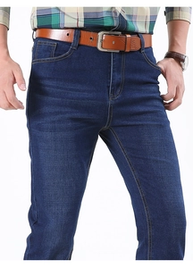 Detailed shot of dark blue men's straight jeans with classic five-pocket design and belt