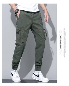 Detail of army green cargo pants featuring multi-pocket design and decorative black straps