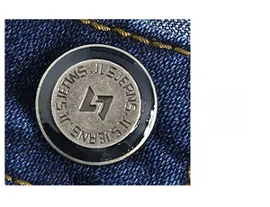 Macro detail of engraved metal button on dark blue stretch denim business casual jeans