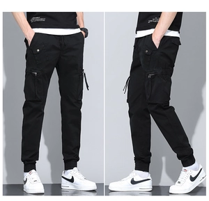 Detail view of black cargo pants featuring large utility pockets and tapered ankle cuffs